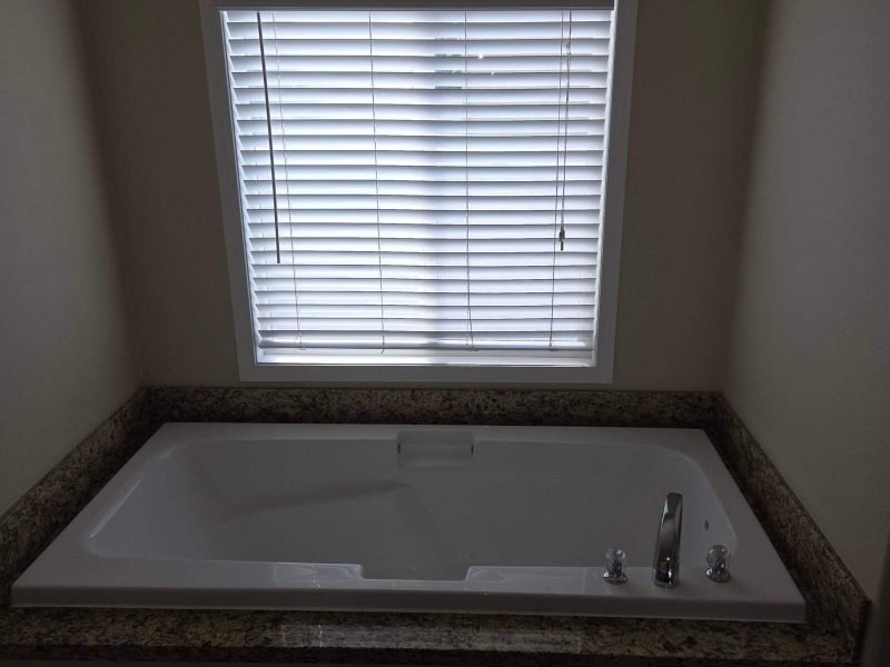 Bathtub with window blinds in a bathroom, showcasing remodeling and home improvement services.
